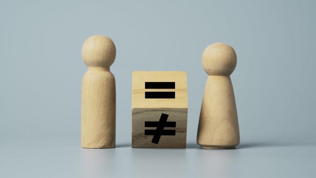 Flipping of unequal to equal sign between man and woman wooden figure. Human and business right concept.