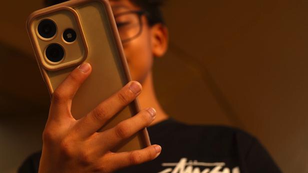 Ein Teenager schaut auf sein Handy.