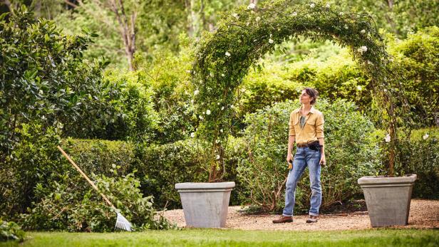 Frau steht im Garten und genießt zufrieden die Aussicht