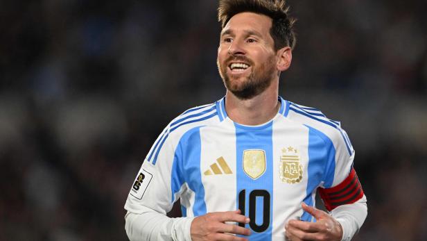 Lionel Messi lächelt in seinem weiß-hellblauen Trikot der argentinischen Nationalmannschaft mit der Rückennummer 10 auf dem Spielfeld.