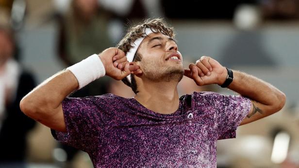 Ein Tennisspieler mit Stirnband hält sich mit geschlossenen Augen die Finger in die Ohren.