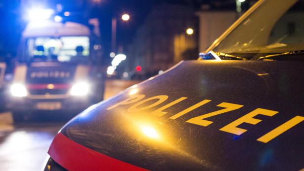 Zwei Polizeifahrzeuge stehen nachts mit eingeschaltetem Blaulicht auf einer Straße.