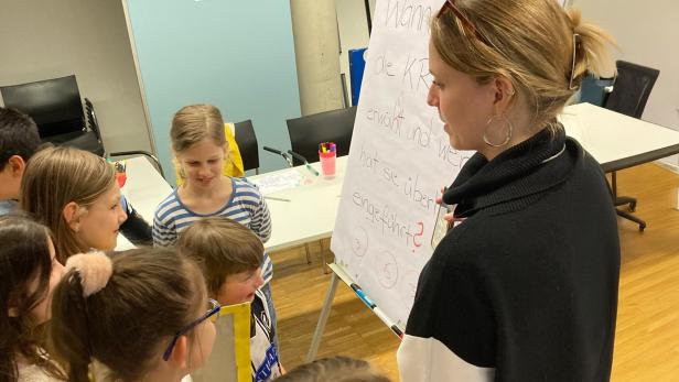 Kinder diskutieren mit einer Pädagogin vor einem Flipchart über Kinderrechte und Beteiligung.