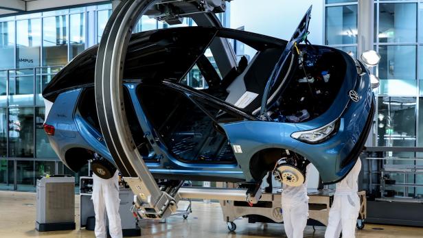 Schräg hängender VW ID.3 mit Monteuren in einer Autofabrik von Volkswagen.