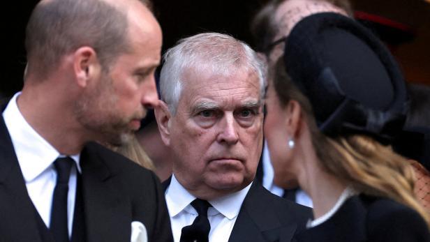 Ex-Prinz Andrew steht zwischen Prinz William und Catherine, Prinzessin von Wales, bei einer offiziellen Veranstaltung in dunkler Kleidung.