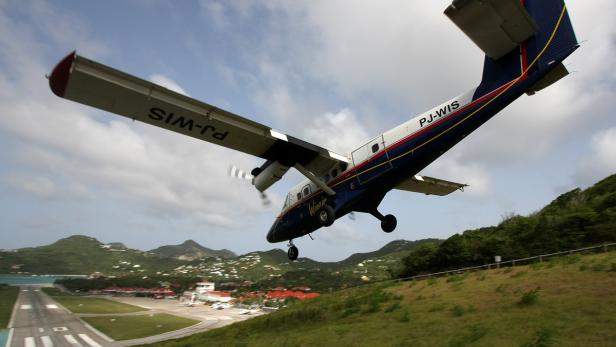 Flugzeug fliegt im Landeanflug knapp über eine Straße am Saint-Barthélemy-Flughafen.