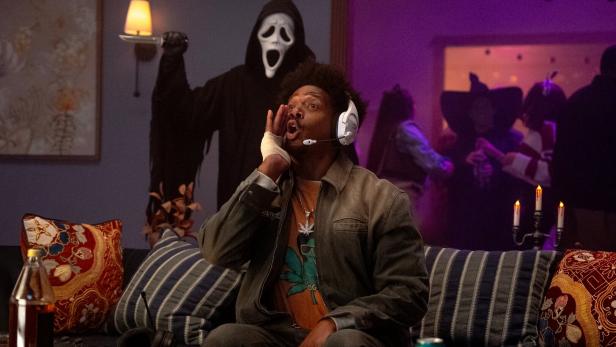 Marlon Wayans sitzt auf der Couch, hinter ihm steht der Killer mit der Maske.