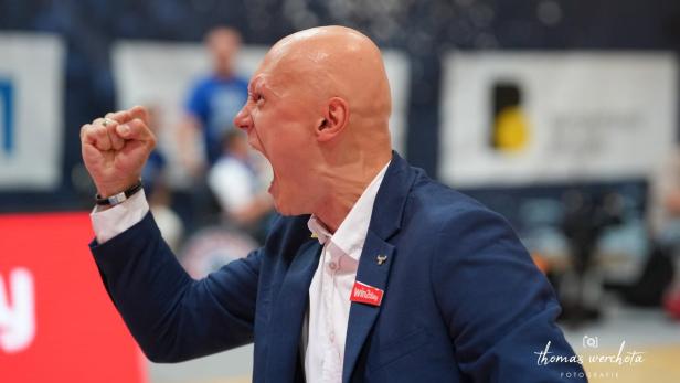 Ein Mann im Anzug ballt die Faust und schreit mit weit geöffnetem Mund, offenbar voller Emotionen.