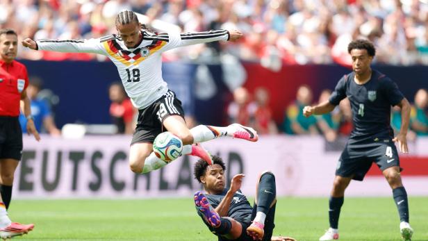 Leroy Sané im deutschen Trikot springt im Zweikampf über einen am Boden liegenden US-amerikanischen Spieler.