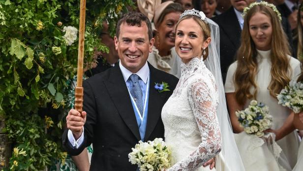 Peter Phillips und Harriet Sperling lächeln bei ihrer Hochzeit, während er einen Regenschirm hält.