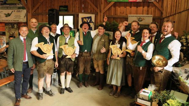 Eine Gruppe in Tracht feiert bei einer Veranstaltung des Breitenfurter Jagdklubs mit Trophäen in einer Holzhalle.