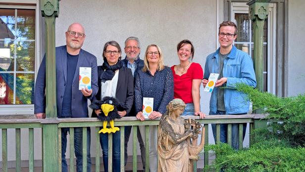 Sechs Personen stehen nebeneinander auf einem Balkon