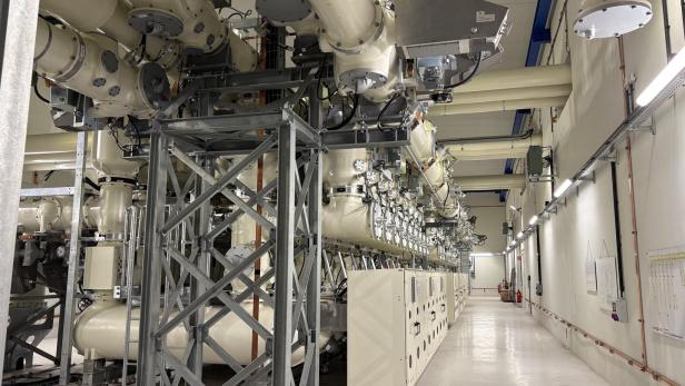 Eine gasisolierte Schaltanlage mit großen, hellen Rohrsystemen und Schaltschränken in einer technischen Halle.
