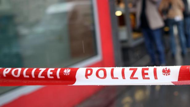 Ein rot-weißes Polizei-Absperrband vor einem Gebäude.