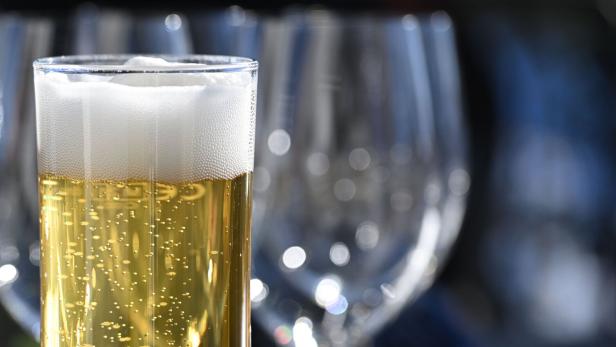 Ein Glas Bier und ein Weinglas stehen auf einem Tisch.