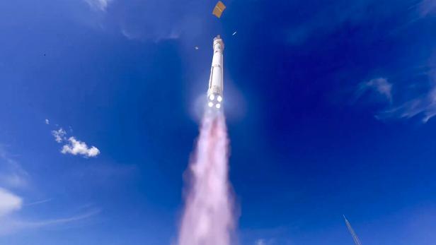 Eine Rakete startet senkrecht in den blauen Himmel und hinterlässt eine Rauchspur.
