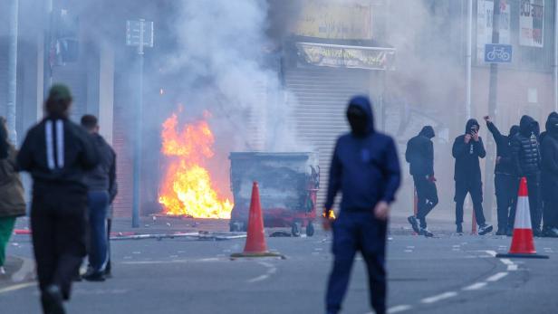 Brennende Wohnhäuser und Autos, vermummte Randalierer: Belfast (Nordirland) ist nach einem Messerangriff von rassistischen Ausschreitungen erschüttert worden.