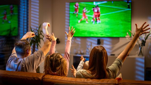 Eine Familie schaut Fußball im Fernsehen und jubelt.