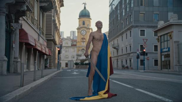 Ein halbnackter Mann posiert mit Robe und Schwert als Gabriele D'Annunzio.