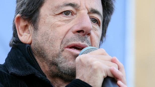 Patrick Bruel spricht in ein Mikrofon.