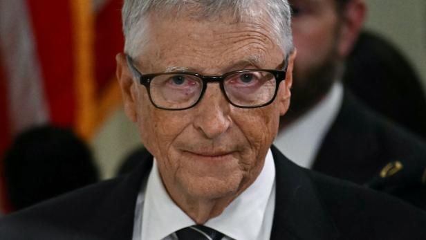 Bill Gates trägt eine Brille, ein weißes Hemd sowie einen dunklen Anzug und blickt ernst in die Kamera.