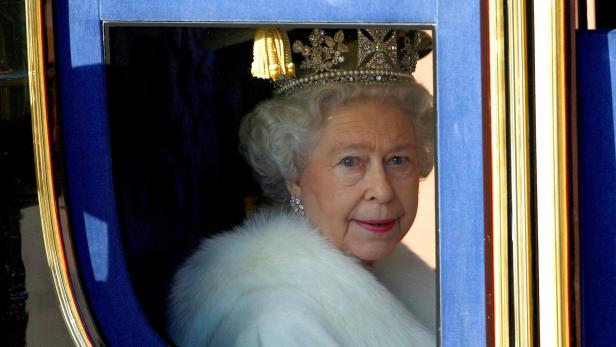 Queen Elizabeth mit einer Krone auf dem Kopf blickt durch das Fenster einer Kutsche