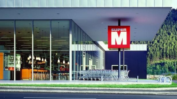 Ein Supermarkt „Super M“ mit Einkaufswagen und einem Café im Eingangsbereich.