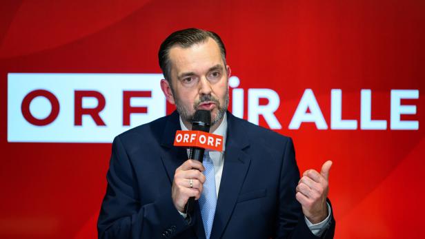 Mann im Anzug spricht vor rotem ORF-Hintergrund ins Mikrofon und gestikuliert.