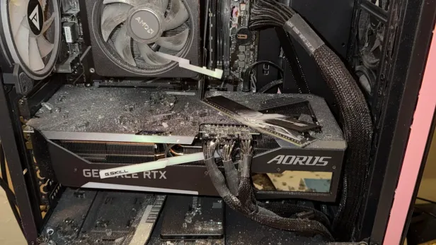 Zerstörter pinker Gaming-PC mit Glassplittern und beschädigten Komponenten auf einem Schreibtisch.