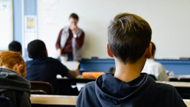 Schulkind im Kapuzenpullover sitzt ind der Klasse