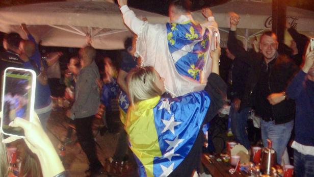 Jubelnde Menschen mit bosnischen Fahnen beim Public Viewing im Freien.