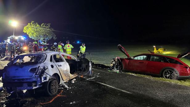 Zwei stark beschädigte Autos nach einem nächtlichen Unfall, Einsatzkräfte und ein Rettungshubschrauber sind vor Ort.
