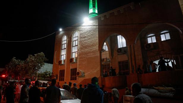 Palestinians gather near a mosque following an incident involving a damaged car that Palestinians say was attacked by settlers, in Burqa