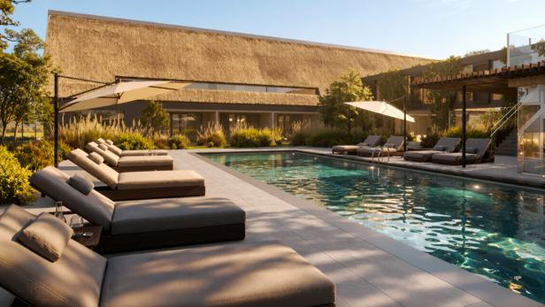 Moderner Pool mit Liegen, Sonnenschirmen und begrüntem Resortgebäude bei blauem Himmel.