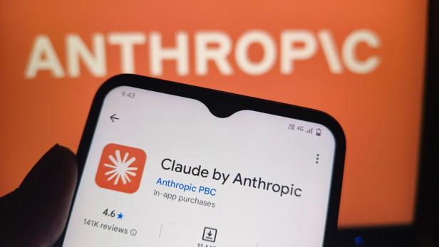 Ein Smartphone zeigt die App-Store-Seite für „Claude by Anthropic“ vor einem Hintergrund mit dem Anthropic-Logo.