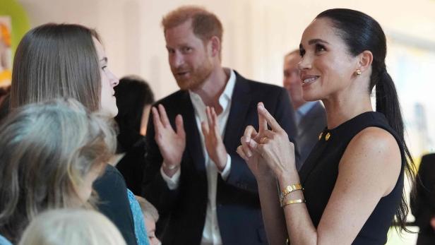 Meghan bei einem Besuch in Melbourne im Gespräch mit Gästen, dahinter Harry