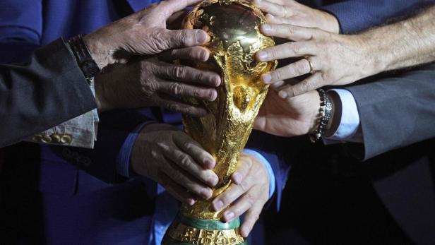 Viele Hände an der goldenen WM-Trophäe