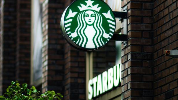 Grün-weißes Starbucks-Schild an der Fassade einer Filiale