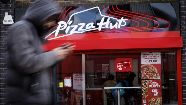 Verwischte Person läuft vor einer Pizza-Hut-Filiale.