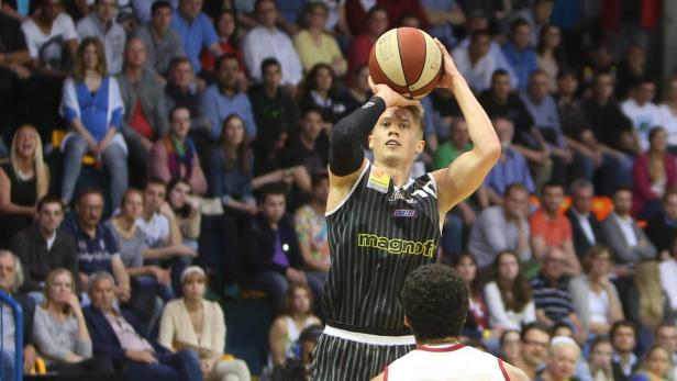 Ein Basketballspieler zielt auf den Korb, während das Publikum zusieht.