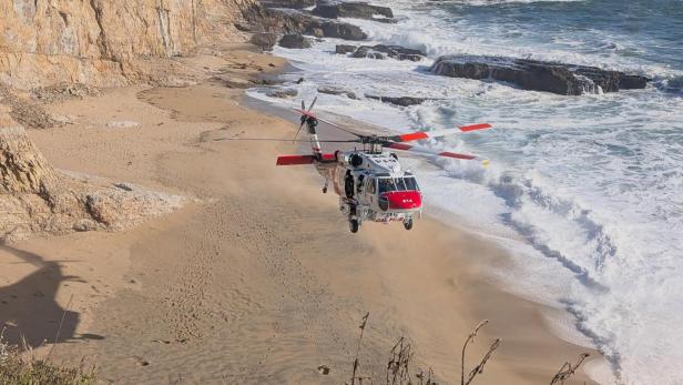 Rettungshubschrauber schwebt über die Brandung am abgelegenen Strand von Santa Cruz County.