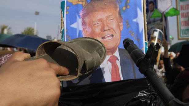 Trump auf einem Screen, Zuschauer werfen Dinge nach ihm.