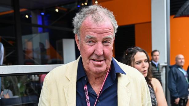 Jeremy Clarkson trägt ein helles Sakko und einen VIP-Ausweis der Formel 1 bei einer Veranstaltung.