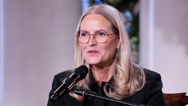 Kronprinzessin Mette-Marit von Norwegen spricht in einem schwarzen Blazer vor einem Mikrofon.