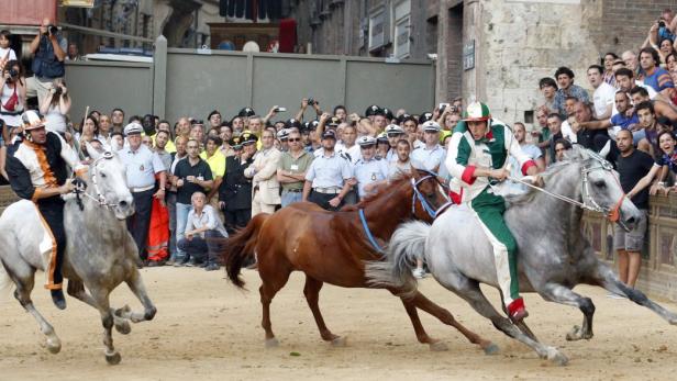 Jockey Giovanni Atzeni (R) of the Oca (Goose) parish leads ahead of Pestifero, the horse of the Pantera (Panther) parish, and jockey Giuseppe Zedde of the Torre (Tower) parish during the Palio race in Siena July 2, 2013. Atzeni won the Palio of Siena. REUTERS/Stefano Rellandini (ITALY - Tags: SOCIETY ANIMALS SPORT)