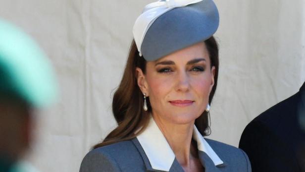 Catherine, Prinzessin von Wales, trägt einen grauen Blazer mit weißem Revers und einen passenden Hut.