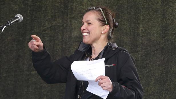 Eine Frau hält eine Rede mit Notizen in der Hand und zeigt mit dem Finger.