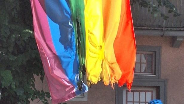 Zerstörte Regenbogenfahne vor einem Haus.
