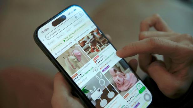 Eine Person tippt auf einem Smartphone in einer Shopping-App mit Produktübersicht.