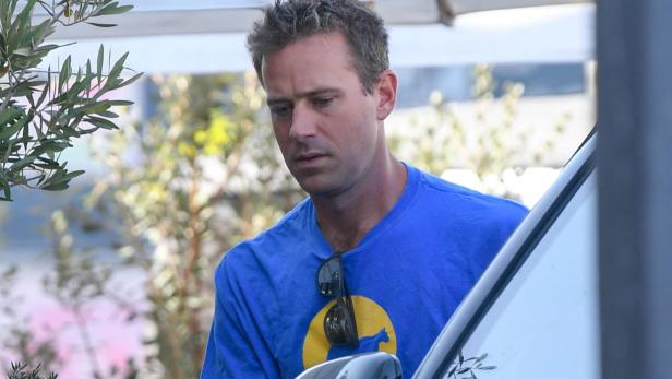 Armie Hammer steht neben einem Auto und blickt angespannt nach unten.